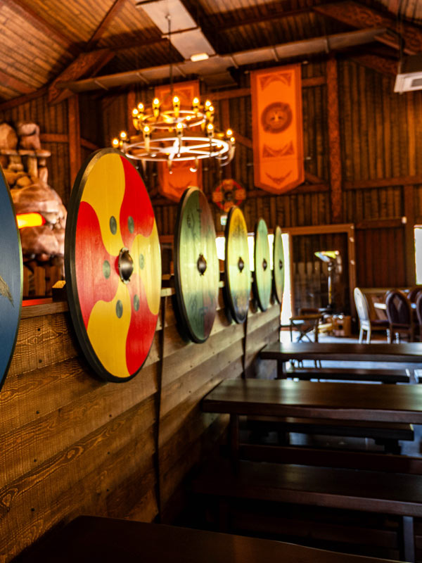Viking shields and wooden bench seating inside the Feasting Hall in Valgard at Paultons Park.