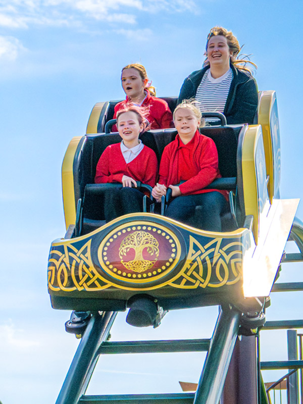 Family riding a Valgard themed rollercoaster at Paultons Park with blue sky overhead.