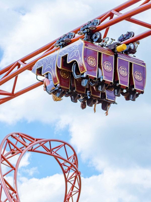 Riders enjoying Drakon rollercoaster at Paultons Park as the train passes beneath the red track