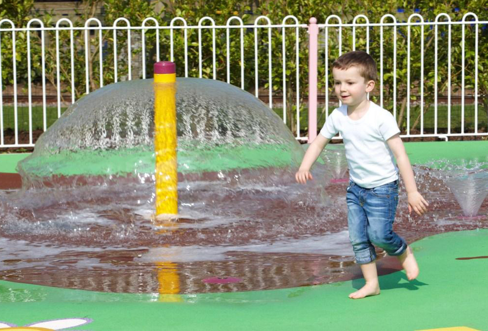 Child playing in the Muddy Puddles water splash area at Peppa Pig World, Paultons Park.