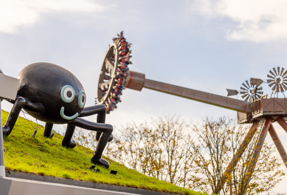 Peppa Pig World at Halloween with Mr Skinny Legs spider decoration and themed rides in the background